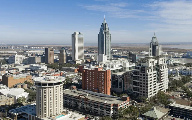 Skyline of Mobile, Alabama, viewed from the west, with downtown buildings along the Mobile River.