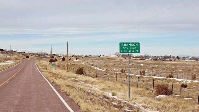 The city limit sign for Branson, Colorado. The town is visible in the background. The road is Colorado State Highway 389. Branson is located in Las Animas County, Colorado.