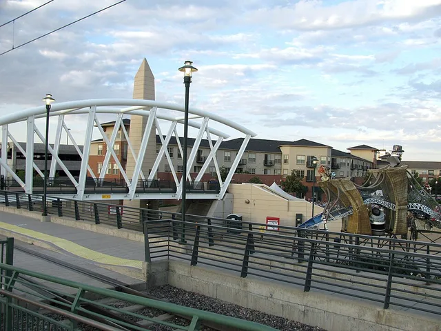The Alexan apartments, outdoor artwork, and the RTD light rail pedestrian bridge can be seen in this picture.