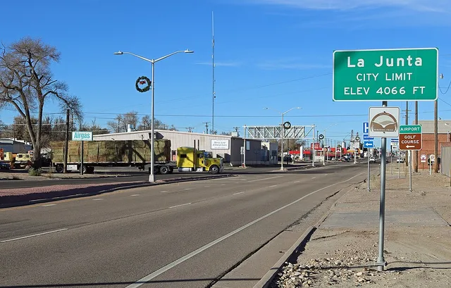 Looking west along East 1st Street ( U.S. Highway 50 ) in La Junta, Colorado . The view includes a La Junta city limit sign, and a hay truck turning on to the street.