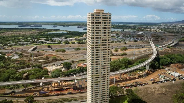 The Honolulu Rail Transit viaduct under construction, seen as it crosses over Interstate H-1 in Pearl City, Hawaii. One of the towers of the Century Park Plaza condominium complex...
