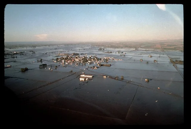 Image Title: Teton Dam Flood - Sugar City Date: June 5, 1976 Place: Sugar City, Idaho Description/Caption: Aerial view of floodwaters moving down the Valley. Medium: color transpa...
