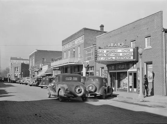 Eldorado, Illinois : Grand cinema, Eldorado Hotel, and further down the street can be seen. Period automobiles are parked diagonally along the brick street.