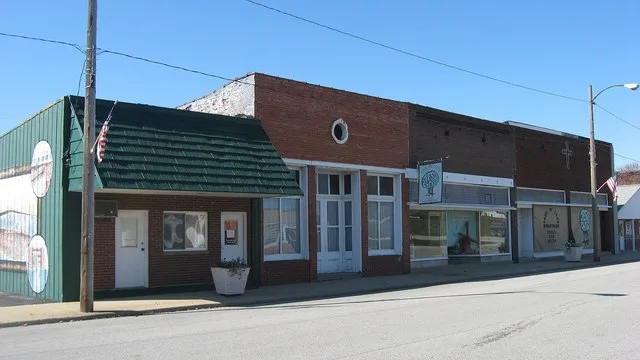 Buildings on the western side of the 100 block of S. Main Street in Hutsonville , Illinois , United States . From left to right, the buildings are (1) Village Hall; (2) Unidentifi...