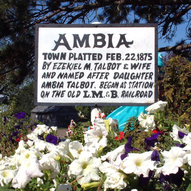 A sign at the corner of Third Street and Elm Street in Ambia, Indiana describes the town's origins. Photo looks northwest. The sign reads: Ambia Town platted Feb. 22, 1875 by Ezek...