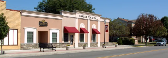 A photo taken on Fifth Street in Fowler, Indiana , looking northeast toward the police department building and the town hall. At right, partly obscured by trees, is the public lib...