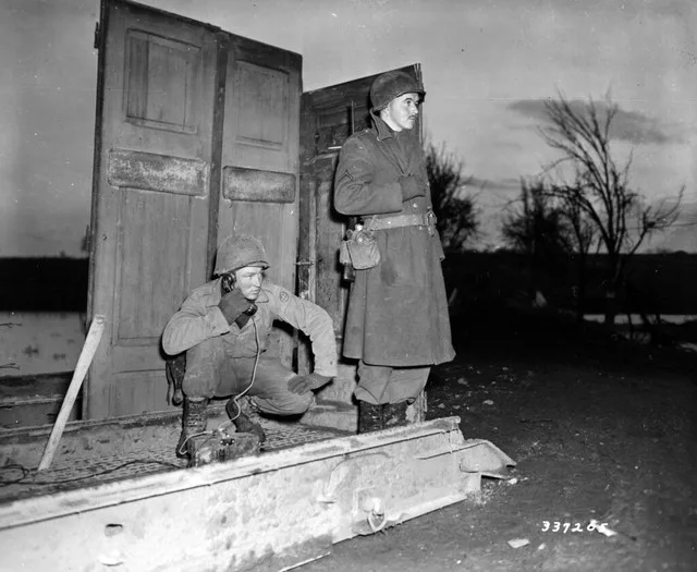 SC 337205 - Pvt. Bill Mels of Sheldon, Iowa, and Pfc. Ben Cole of Forest City, North Carolina, stand guard with an improvised shelter to shield them from the wintry blasts.