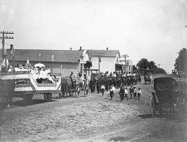 Fourth of July parade in Alta Vista, Kansas. William F. Kahle is seen hauling a large log behind the Royal Neighbors and Modern Woodmen of America float.