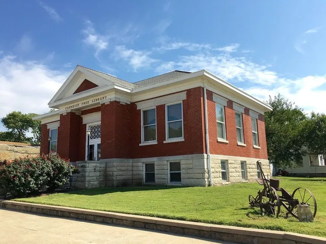 Carnegie Free Library, Burlington, Kansas, Coffee County 201 N 3rd Street, Burlington, KS This is the view from the corner which includes an antique horse-drawn hoe & seeder on th...
