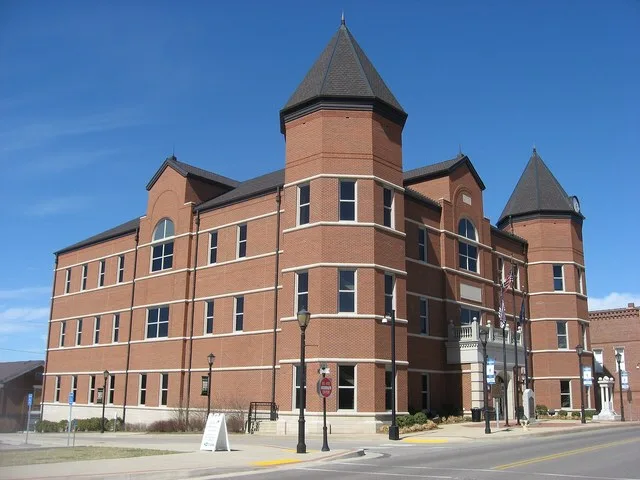 Front and southern side of the Trigg County Courthouse , located on the western corner of the junction of Main and Monroe Streets in Cadiz , Kentucky , United States . It was buil...