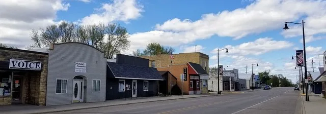 Businesses along Central Ave N in Brooten, Minnesota. Businesses visible include the Bonanza Valley Voice newspaper, Michelle's Accountables, the U.S. Post Office, and Rustic Stab...