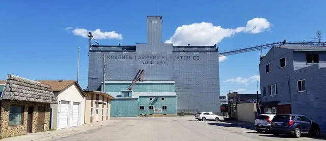 Buildings on Main Street in Sabin, Minnesota, including the Sabin Community Center (left), Kragnes Farmers Elevator Co. (center) and the Crow Bar & Grill (right).