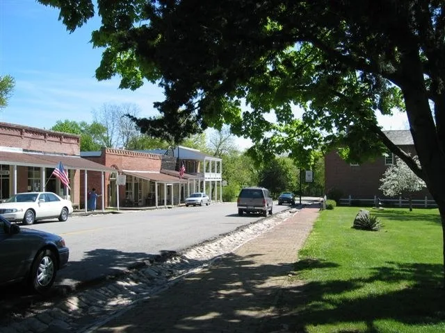 Boardwalk stores on left, J. Huston Tavern on right. Stone gutters laid by slaves in 1858 line the street.