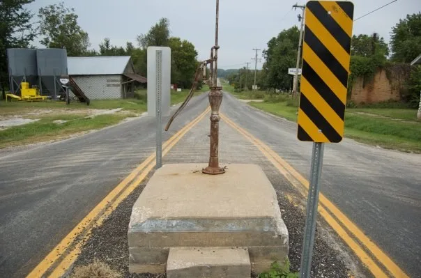 A 1904 community hand pump surviving modern encroachment in 2010 on the middle of Main Street at La Russell, Missouri.
