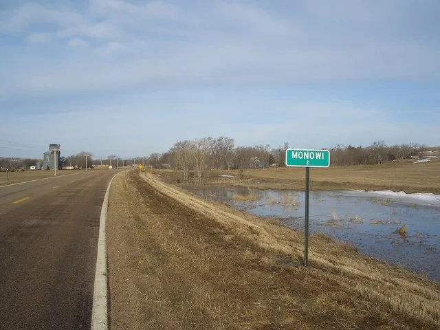 Sign announcing the population (2) of Monowi, Nebraska , USA, seen as one enters the town from the east. Some of the buildings of Monowi are visible in the background.