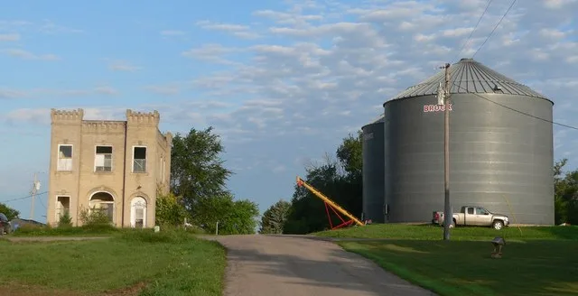 Wayne County Bank building and grain bins in Sholes, Nebraska ; seen from the east.