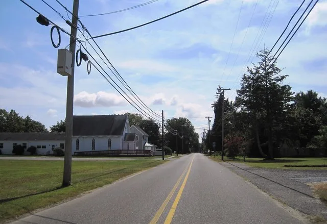 Photo of southbound County Route 611 (Main Street) in Corbin City , New Jersey showing signage for the upcoming intersection with CR 649 and the Corbin City Baptist Church. Photo...