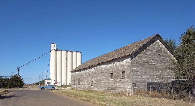 Grain elevator and wooden building at the border of Texas and New Mexico. Elevator is in Texico, New Mexico whereas wooden building is in Farwell, Texas.