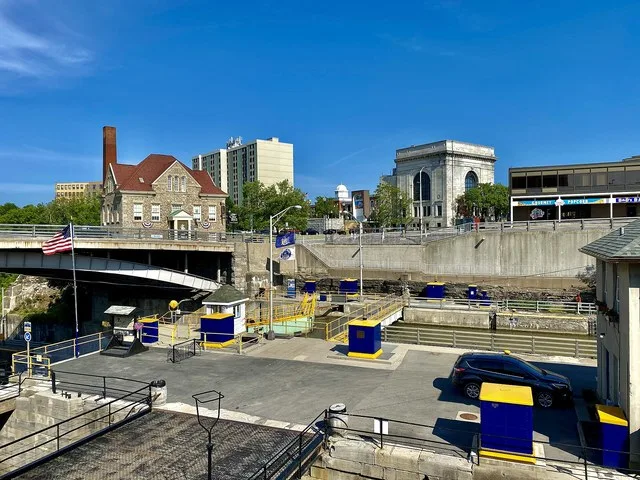 A view over the downtown district of Lockport, New York as seen from a bench across from Lake Effect Ice Cream on Canal Street on a June 2021 evening. In the foreground is the Eri...