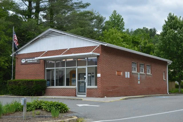 Front and northern side of the Crossnore post office, located on Crossnore Drive at Fountain Circle in Crossnore , North Carolina , United States .