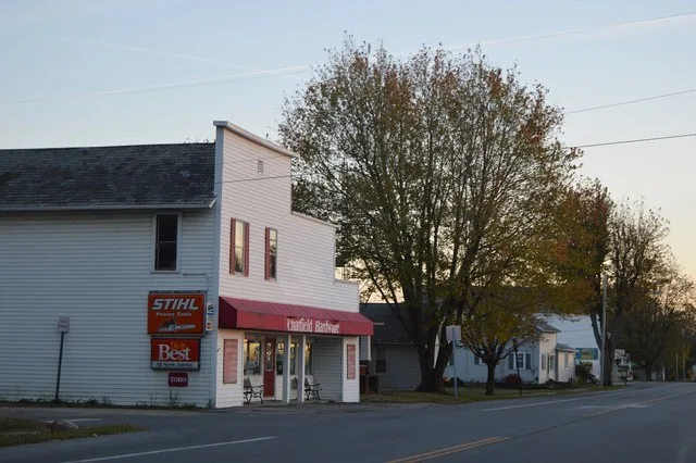 Hardware store and houses in Chatfield , Ohio , United States , seen looking south on Sandusky Avenue ( State Route 4 ) at Fourth Street.