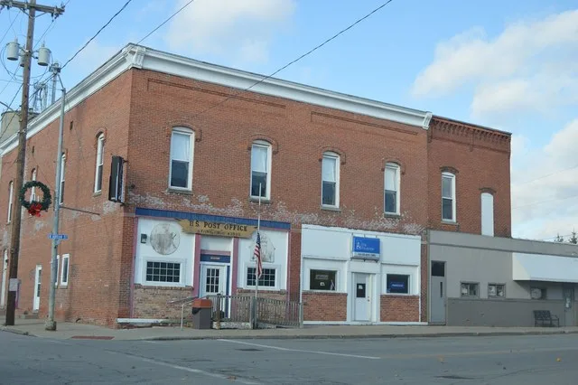 Commercial buildings (including the post office) on the western side of Adrian Street seen from the Morenci Street intersection in Lyons , Ohio , United States .