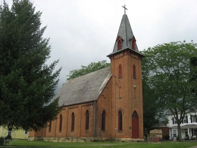 Front and southern side of Trinity Episcopal Church , located on the southwestern corner of the intersection of Sugar and High Streets in McArthur , Ohio , United States . Built i...