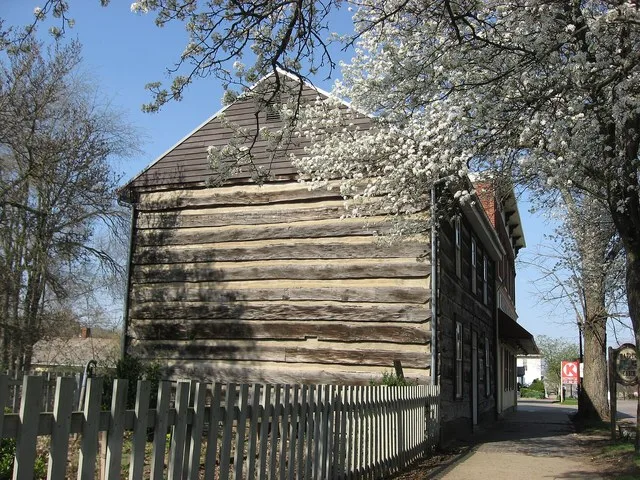 Front and eastern side of the William Rainey Harper Log House , located along E. Main Street ( U.S. Route 40 ) in downtown New Concord , Ohio , United States . Built in 1825, it i...