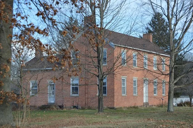 Western side and front of the Thomas Johnson House , located on the northern side of Main Street ( State Route 93 ) at the College Avenue intersection in Plainfield , Ohio , Unite...