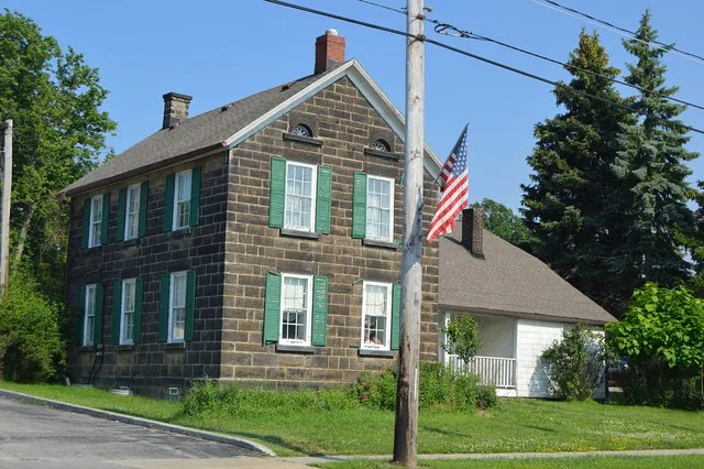 Western side and front of the John Froelich House , located at 7095 Broadview Road ( State Route 176 ) in Seven Hills , Ohio , United States . Built in 1843, it is listed on the N...