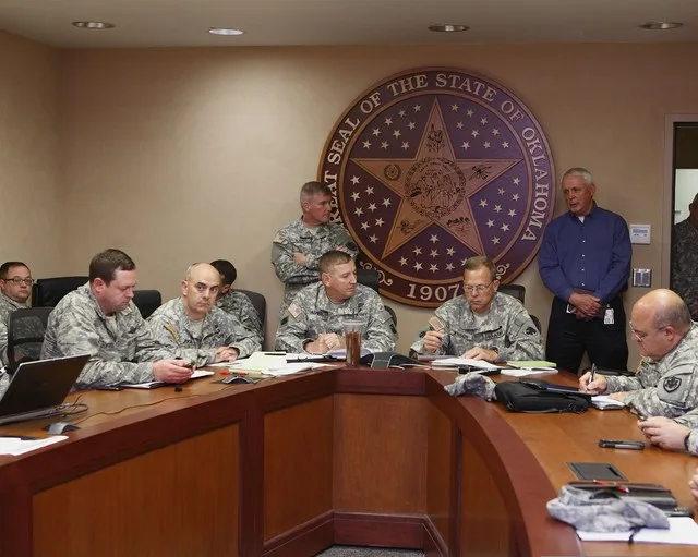 Larry Stice, standing right, the director of state resource management, gives a status update to U.S. Army Brig. Gen. Robbie Asher, the director of the Joint Staff, Oklahoma Natio...