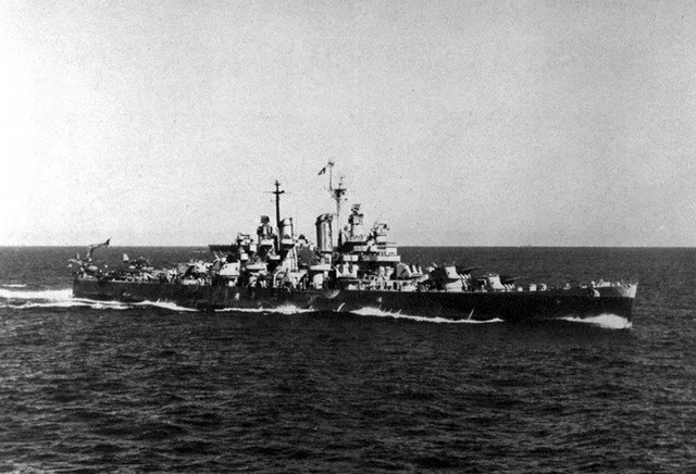 The U.S. Navy light cruiser USS Oklahoma City (CL-91) underway. An Independence -class carrier is barely visibile above the aft turrets.