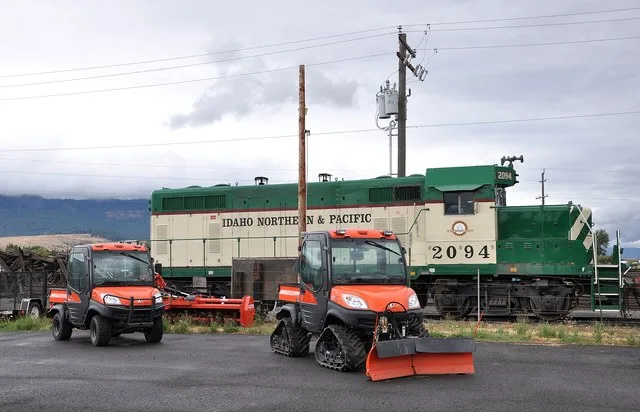 Locomotive and other vehicles along Island Avenue, Oregon Route 82 , in Island City , Oregon, in the United States. The locomotive is an EMD GP7 (INPR #2094, ex-ATSF #2773).