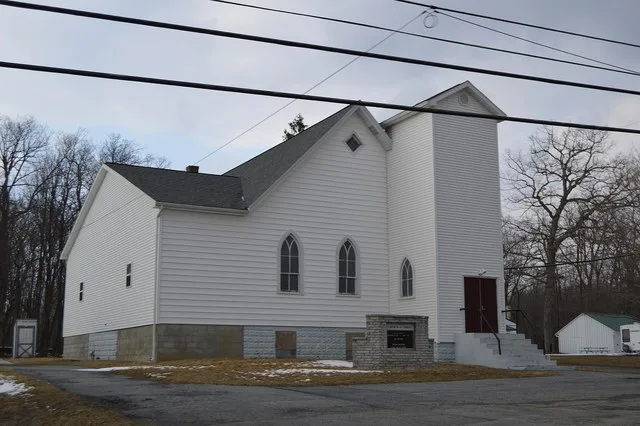 Western side and front of the Broad Top Church of Christ, located at 5117 Railroad Avenue ( Pennsylvania Route 913 ) in Broad Top City , Pennsylvania , United States .