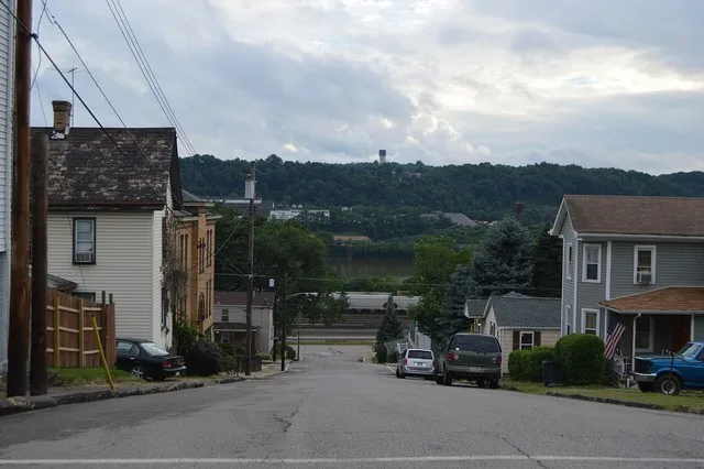 A typical street scene in Freedom , Pennsylvania , United States : vernacular houses line a street that climbs a steep hillside out of the Ohio River floodplain, with the Conway Y...