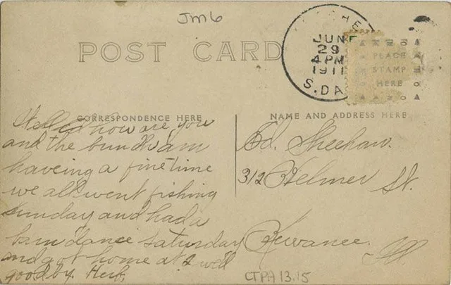 Postcard consisting of a man driving an automobile with various views of people and places from Letcher decorating the side of the vehicle.