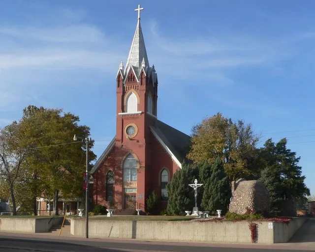 St. Wenceslaus rectory (left, largely obscured by trees) and church, located at northwest corner of Lidice and Yankton Streets in Tabor, South Dakota; seen from the southeast, loo...