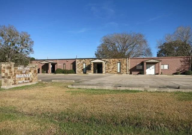 Photo shows the Village of Bonney municipal buildings (Community Center, Police Station, City Hall) at 19025 FM 521, Bonney, Texas. The view is toward the east.