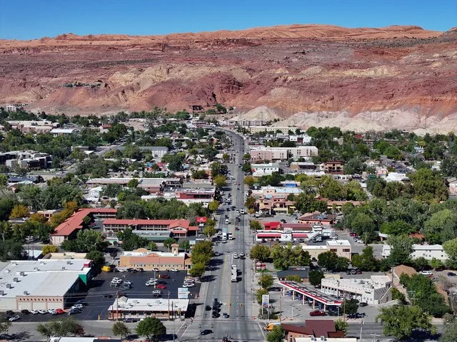 View north along Main Street (U.S. Highway 191) in Moab, Utah, with the downtown below the red rock cliffs and mesas of surrounding canyons.
