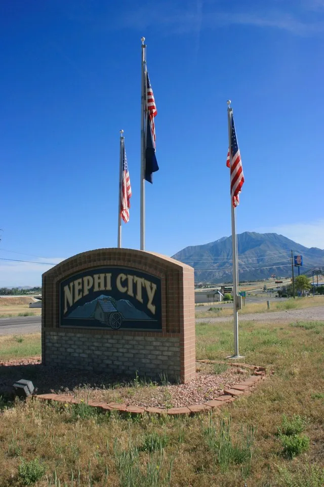 Photograph of the sign at the entrance to the city of Nephi , Juab County , Utah , United States , with in the distance, as viewed from Utah State Route 28 on the south side of th...