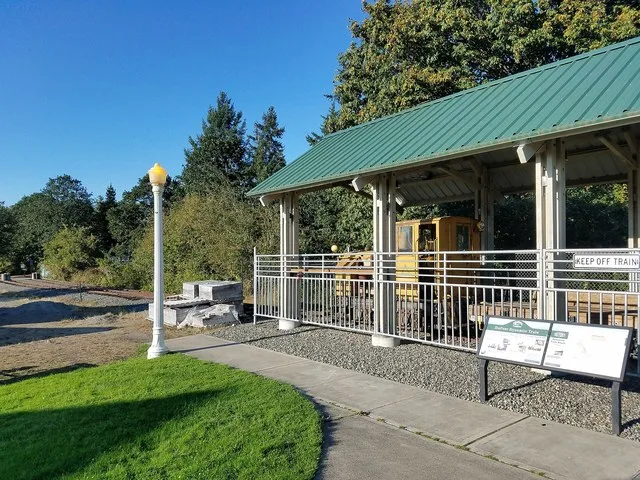 Exhibit featuring old narrow-gauge locomotive and dynamite train used by the DuPont chemical company during the company town days in DuPont, Washington, USA. The exhibit is behind...