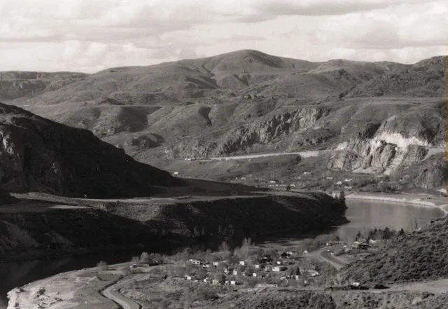 Black and white photograph of small town next to a river bend with bare mountains rising in the background Small town, probably Elmer City, just below Coulee Dam. Taken c 1945. Ke...