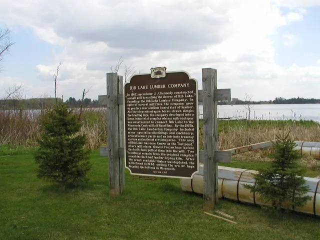 Rib Lake Lumber Company historic marker at public boat landing on Highway 102. Inscription: In 1882, speculator J.J. Kennedy constructed a small mill along the shores of Rib Lake...
